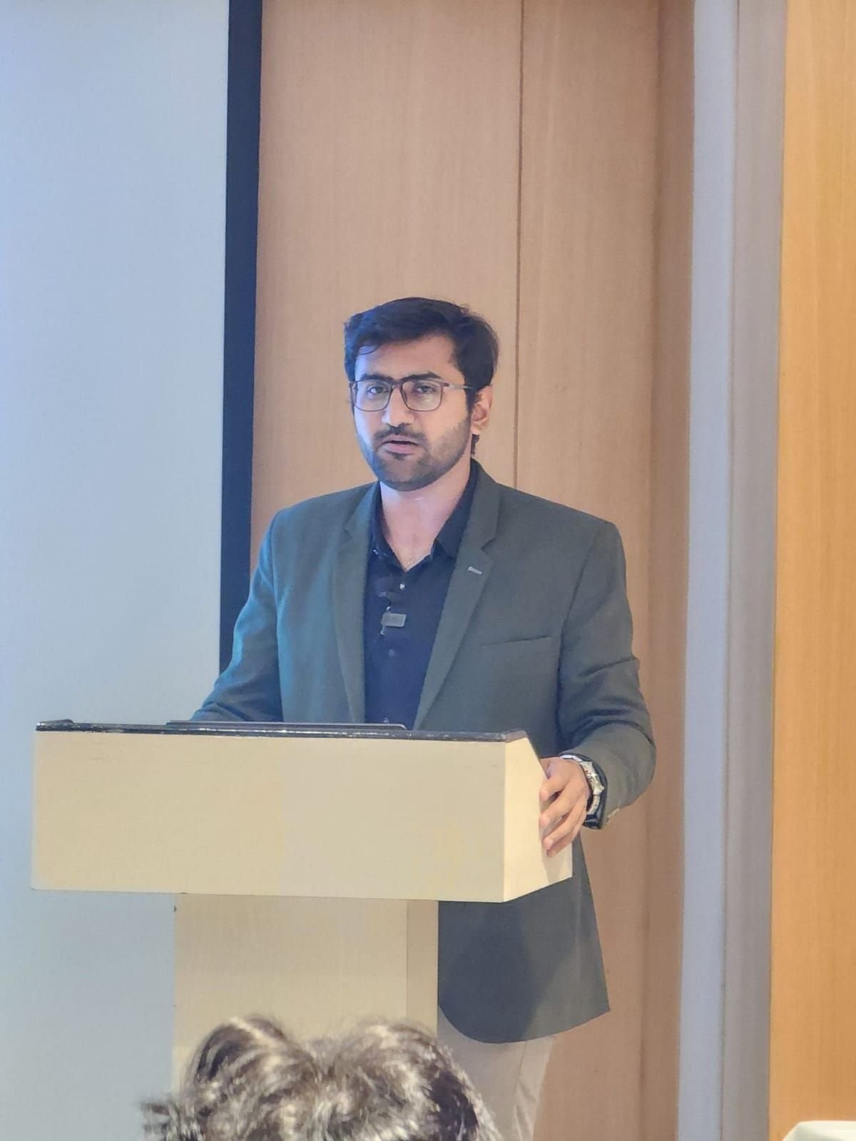 Viren Gajjar speaking at a podium during a corporate training session